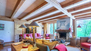 Ein gemütliches Wohnzimmer mit Holzbalken, Kamin und farbenfroher Einrichtung.
