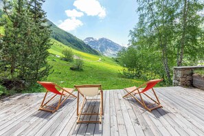 A wooden deck with two red lounge chairs facing a mountainous landscape. - Praz de la Legettaz C & D – Stunning Duplex with Panoramic Views (Val-d'Isère)