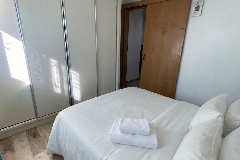 A hotel room with a bed, a wardrobe, and a door.