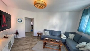Un salon avec un canapé, une table basse et un téléviseur posé sur un meuble.