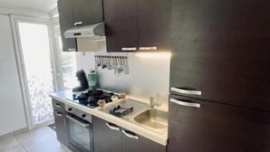 Cocina moderna con armarios oscuros, una encimera y una alfombra verde.