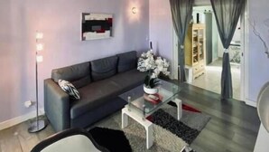 Una sala moderna con sofá, mesa de centro y un separador de vidrio.