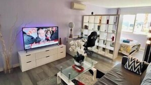 Una sala de estar moderna con un televisor de pantalla plana, un sofá, una mesa de centro y una estantería.