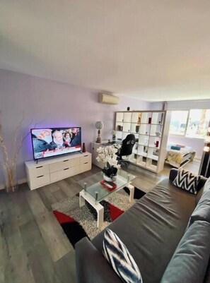 Ein modernes Wohnzimmer mit Flachbildfernseher, einer Couch, einem Couchtisch und einem Bücherregal.