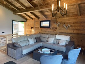 Ein stilvolles Wohnzimmer mit Ecksofa, Couchtisch und einer Kronleuchter.