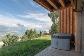 Ein Whirlpool auf einer Holzterrasse mit Blick auf die Berge.