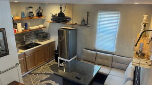 A compact kitchen with a refrigerator, microwave, and toaster. There's a sofa and a small table with a remote control. - The Dutchmen 420 Friendly. Loft tiny house  (Ocean View)