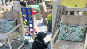 A deck with three dogs lying down, surrounded by outdoor furniture and potted plants. - The Dutchmen 420 Friendly. Loft tiny house  (Ocean View)