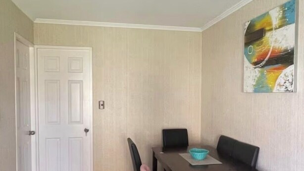 Un comedor con una mesa, sillas y un cuadro en la pared.