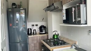 Una cocina compacta con refrigerador, estufa, microondas y lavadora.