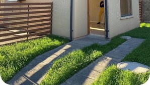 Una casa de dos pisos con fachada marrón, una puerta visible y un ventanal pequeño.