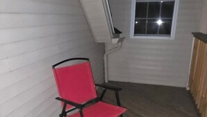 Eine Holzterrasse mit einem roten Stuhl und einem kleinen Tisch.