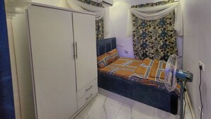 Une chambre à coucher comprenant un lit, une armoire, un appareil de climatisation et un luminaire au plafond.