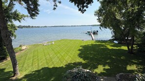 A grassy area with a dock extending into a lake, surrounded by trees. - Spectacular Lake Minnetonka waterfront home, 4 bedroom w/ 8 month lease required (Wayzata)
