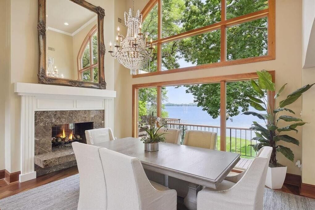 A dining area with a fireplace, large windows, and a view of the outdoors.