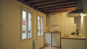 Eine kompakte Küche mit integriertem Kühlschrank, einem kleinen Spülbecken und einer Arbeitsplatte.