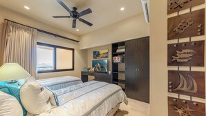 A bedroom with a bed, a desk, a wardrobe, and a wall with decorative metal pieces. - CCV - 2BR Ocean-View Condo w/ Balcony, Golf & Pools at Quivira - Cabo San Lucas (Cabo San Lucas)