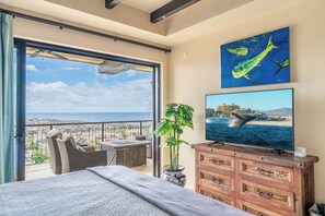 A hotel room with a balcony, a bed, a television, a dresser, and a painting. - CCV - 2BR Ocean-View Condo w/ Balcony, Golf & Pools at Quivira - Cabo San Lucas (Cabo San Lucas)