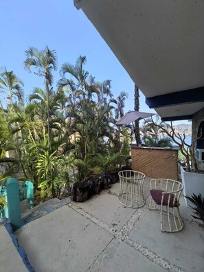 Ein Patio mit Gartenmöbeln, einem Holzzaun und Palmen.