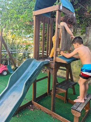 Eine Holzspielkonstruktion mit Rutsche und Kletterelementen.