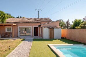 Een huis met een zwembad, terras en een overdekte zithoek.