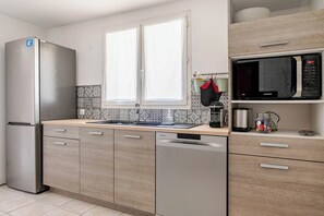 Een moderne keuken met een roestvrijstalen koelkast, een magnetron en een vaatwasser.