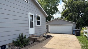 A residential house with a garage, a front door, and a small front yard with a planter and a bicycle. - 4-BR2-BA House INSIDE Iowa State fair! With jetted tub for 2 (Des Moines)