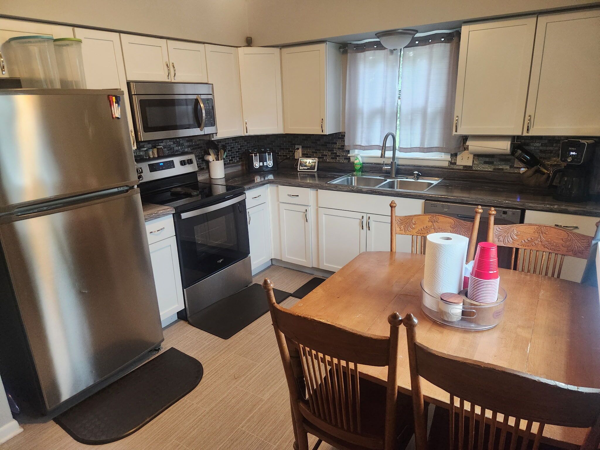 A compact kitchen with a refrigerator, microwave, oven, and a coffee machine.