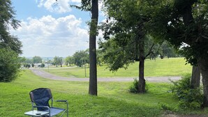 A grassy outdoor area with a fire pit, a folding chair, and a playground structure. - 4-BR2-BA House INSIDE Iowa State fair! With jetted tub for 2 (Des Moines)