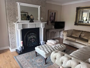 A living room with a fireplace, a television, a sofa, and a decorative mirror. - Golf enthusiasts- Gorgeous 4bedroom house in charming countryside. (Dromhane)