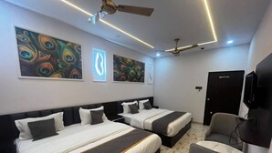 A hotel room with two beds, a TV, and artwork on the walls.