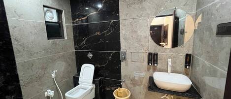 A modern bathroom with a toilet, bidet, sink, and mirror.