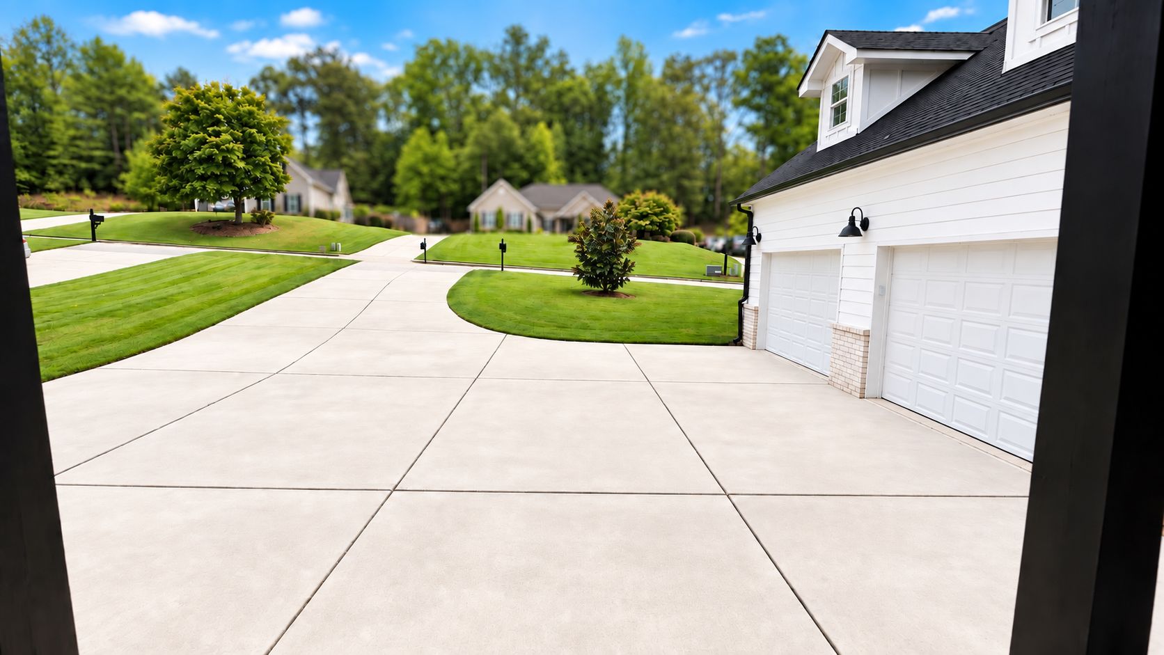 A residential driveway with a garage, a lawn, and a tree.