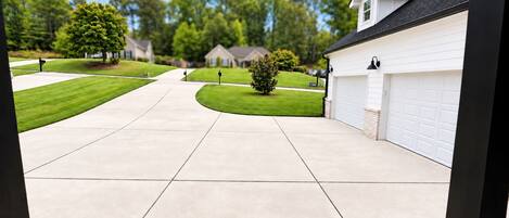 A residential driveway with a garage, a lawn, and a tree.