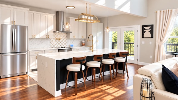 A modern kitchen with a central island, stainless steel appliances, and wooden bar stools.