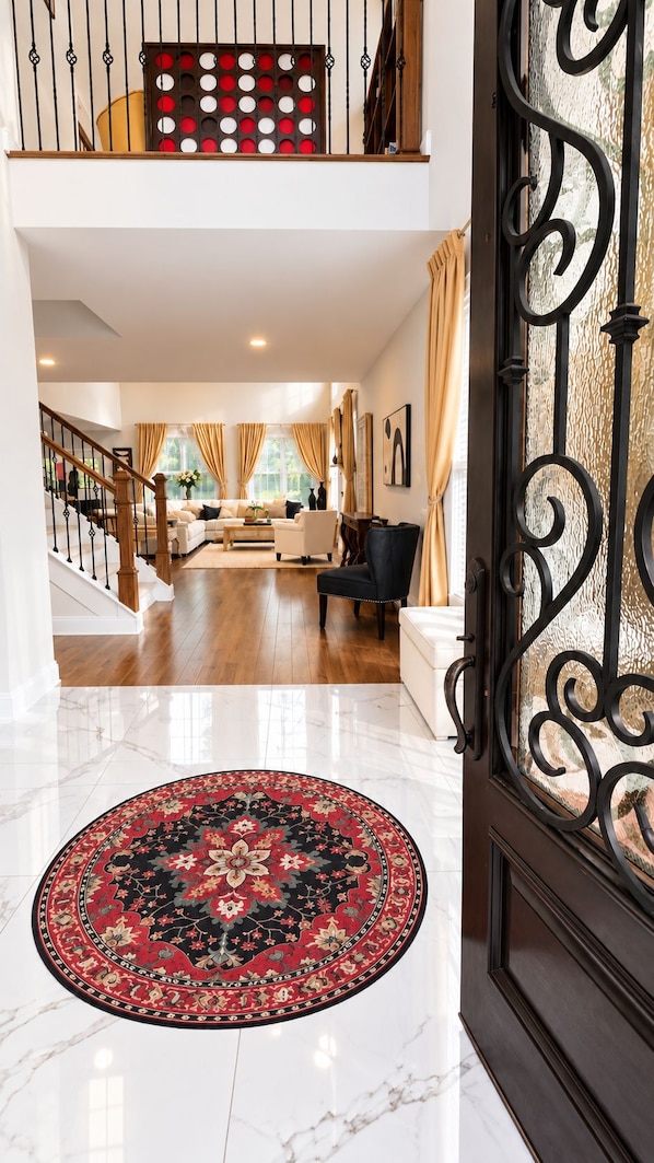 A spacious living area with a staircase, a patterned rug, and a decorative metal gate.