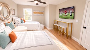 A bedroom with two beds, a TV, and a ceiling fan.