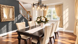 A dining room with a dark wooden table, white upholstered chairs, a vase with flowers, and a chandelier.