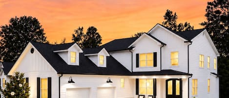 Une maison à deux étages avec un garage, une véranda et une pelouse bien entretenue.