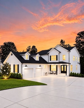 A two-story house with a garage, a covered porch, and a well-maintained lawn.