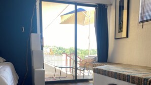 A room with a bed, a cowhide rug, a balcony with a view, and a framed picture on the wall.