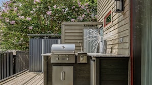 An outdoor kitchen with a grill, storage cabinets, and a decorative plant. - Charming Lakeside Cabin / BBQ Grill / Pickleball (Lake Travis)