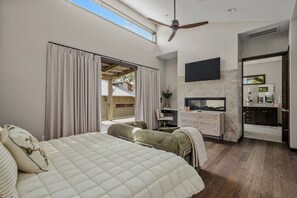Quarto com uma cama grande, televisão, escrivaninha e banheiro.