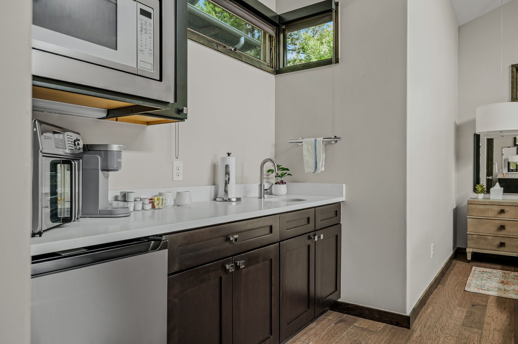 A modern kitchen with a built-in dishwasher, a sink, and dark wooden cabinets.
