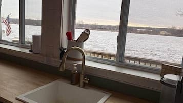 Una cocina con vista a un cuerpo de agua, un lavabo y un grifo.