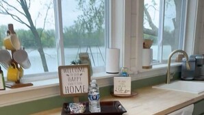 A kitchen with a wooden countertop, green cabinets, a dishwasher, and a window with a view of trees.