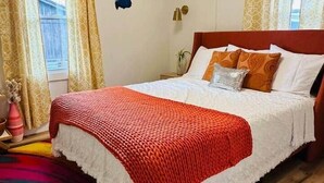 Une chambre à coucher avec un lit, un tapis coloré, des rideaux et des éléments décoratifs sur les murs.