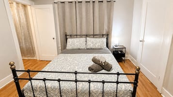 A bedroom with a bed, curtains, a nightstand, and a door.