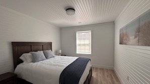 Une chambre à coucher avec un lit en bois, une fenêtre et un tableau accroché au mur.