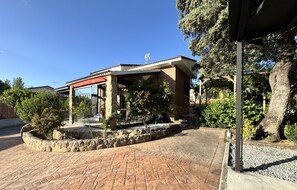A covered outdoor area with stone pillars, a brick pathway, and surrounding greenery. - Private chalet with pool, barbecue and fireplace, 1 hour from Madrid (Maello)